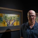 Artista Toba junto a sus cuadros en la galeria
